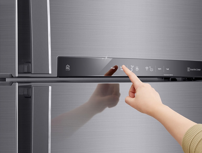 Mano che tocca il pannello di controllo di un frigorifero LG in acciaio inox con funzioni WiFi e Inverter Linear.